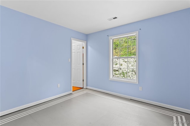 unfurnished room with concrete flooring, visible vents, and baseboards