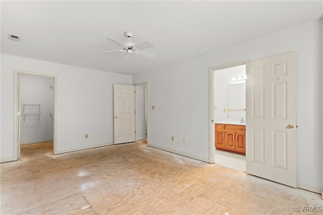 unfurnished bedroom featuring visible vents, baseboards, a spacious closet, a ceiling fan, and ensuite bath