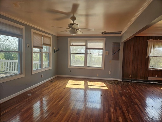 empty room with dark wood-style floors, baseboards, ornamental molding, and a ceiling fan