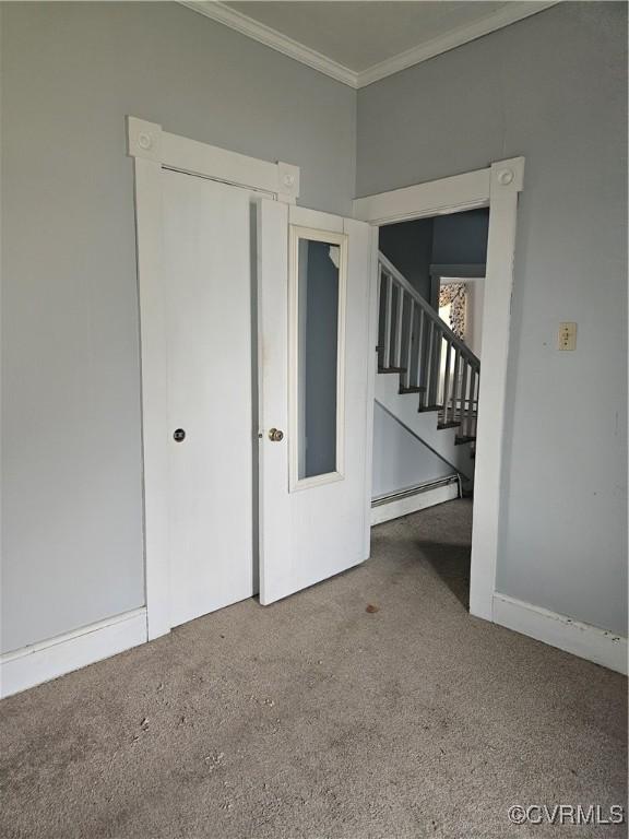 unfurnished room with ornamental molding, a baseboard radiator, carpet, and stairs