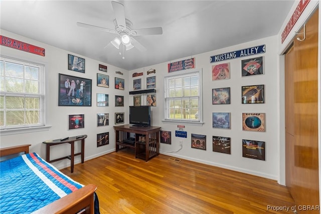 bedroom featuring wood finished floors, baseboards, multiple windows, and visible vents