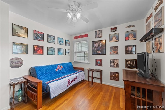 living area featuring baseboards, wood finished floors, and ceiling fan