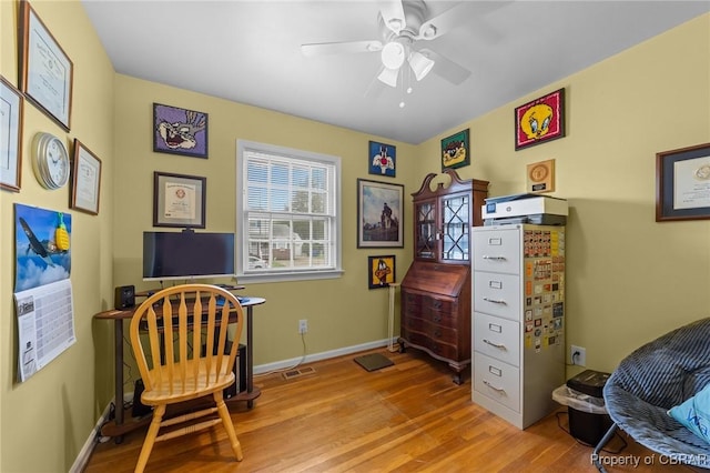 living area with wood finished floors, baseboards, and a ceiling fan