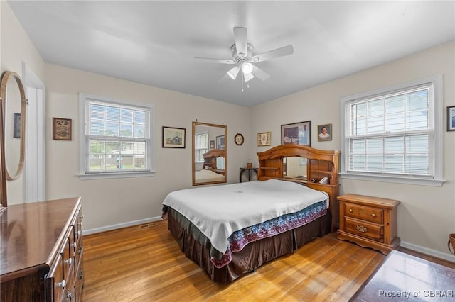 bedroom featuring baseboards, multiple windows, light wood-style floors, and a ceiling fan