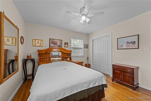 bedroom with a closet, baseboards, light wood-type flooring, and ceiling fan