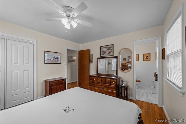 bedroom featuring connected bathroom, a closet, a ceiling fan, wood finished floors, and baseboards