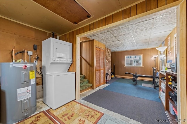 interior space with laundry area, stacked washer and dryer, wood walls, and water heater