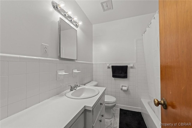 full bathroom featuring tile walls, toilet, vanity, wainscoting, and tile patterned flooring