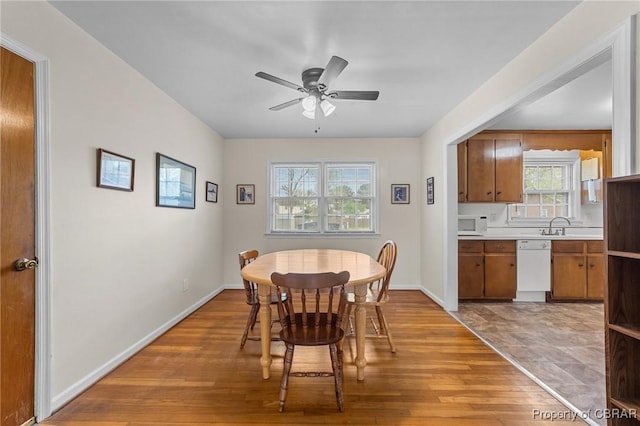 dining room with light wood-style floors, baseboards, and a ceiling fan