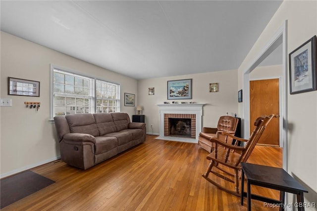 living room with light wood-style floors, a fireplace, and baseboards