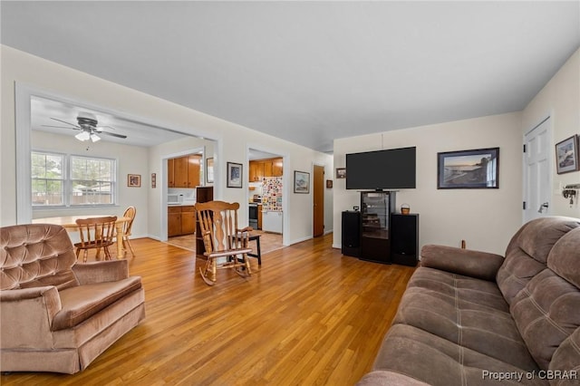 living area with light wood-style floors and ceiling fan