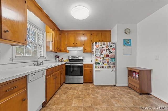 kitchen with under cabinet range hood, white appliances, brown cabinets, and a sink