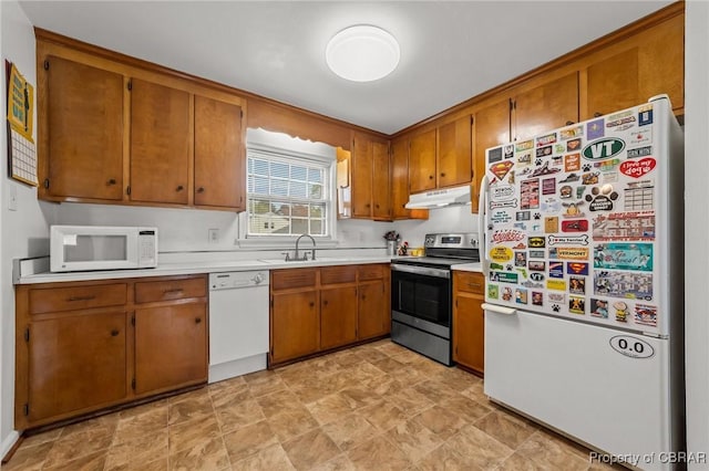 kitchen with a sink, light countertops, white appliances, under cabinet range hood, and brown cabinetry