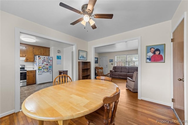dining area featuring light wood-style flooring, ceiling fan, and baseboards