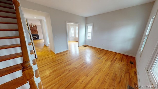 empty room with visible vents, baseboards, stairway, and light wood finished floors