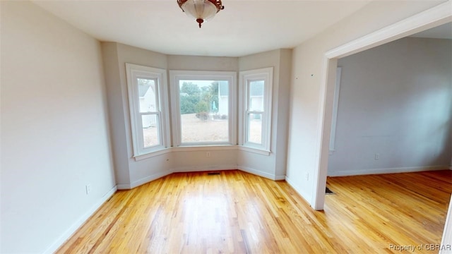 unfurnished room with baseboards and light wood-type flooring