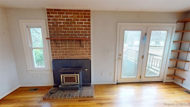 living area with visible vents, a wood stove, wood finished floors, and baseboards