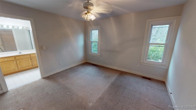 spare room featuring light carpet, a sink, baseboards, and a ceiling fan