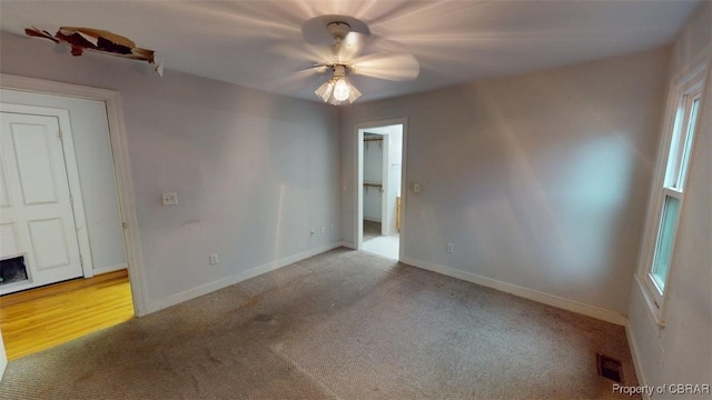 carpeted spare room with visible vents, baseboards, and ceiling fan