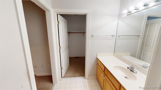 bathroom featuring tile patterned floors, a walk in closet, vanity, and baseboards