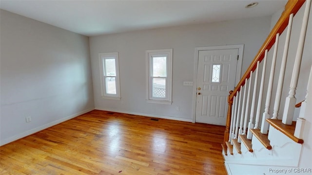 foyer entrance with stairs, visible vents, baseboards, and wood finished floors