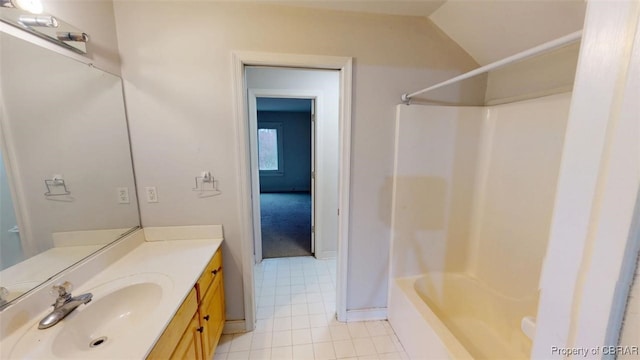 bathroom featuring tub / shower combination, vanity, baseboards, and vaulted ceiling