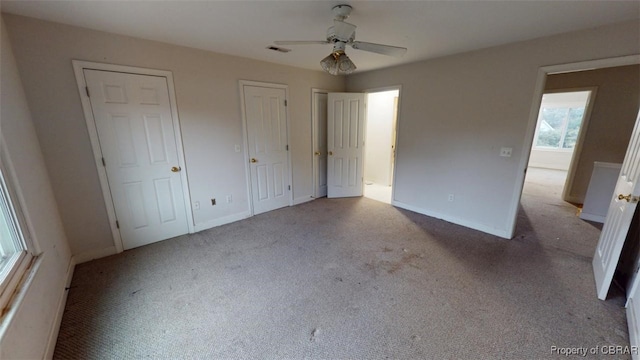 unfurnished bedroom with carpet floors, baseboards, two closets, and visible vents