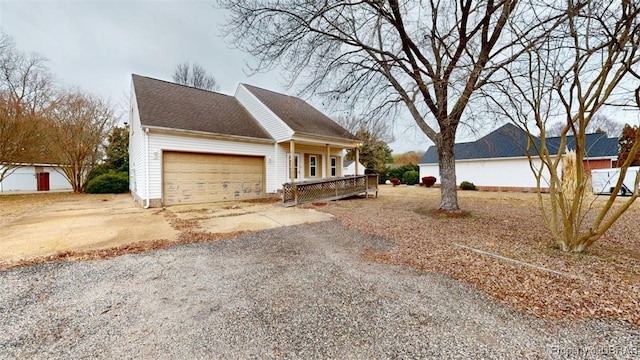 view of front of property with an attached garage, roof with shingles, driveway, and covered porch