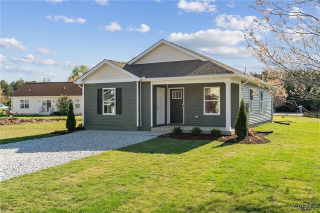 ranch-style house with roof with shingles, a porch, a front lawn, and gravel driveway