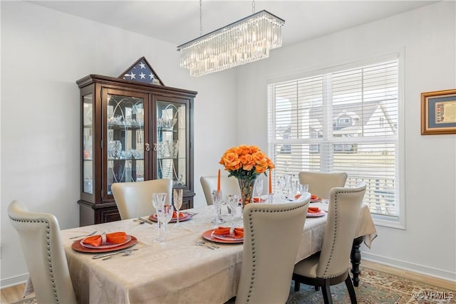dining room featuring baseboards, a notable chandelier, and wood finished floors