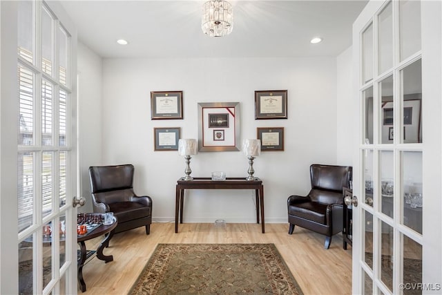 living area featuring baseboards, a chandelier, light wood-style floors, recessed lighting, and french doors