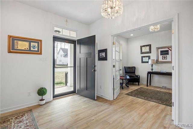 entrance foyer with a chandelier, light wood-type flooring, and baseboards