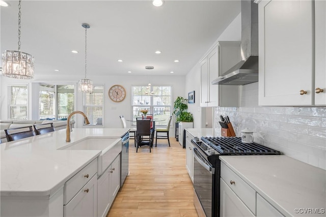 kitchen with wall chimney range hood, gas range, light countertops, and a chandelier