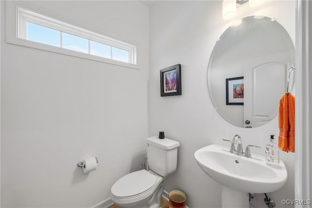 half bathroom featuring baseboards, a sink, and toilet