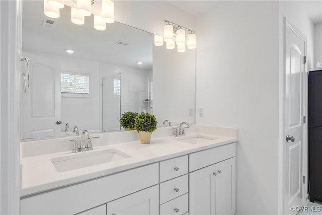 bathroom with a sink, visible vents, a shower stall, and double vanity