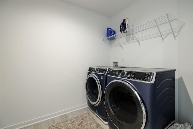 laundry area with light wood-style floors, separate washer and dryer, laundry area, and baseboards