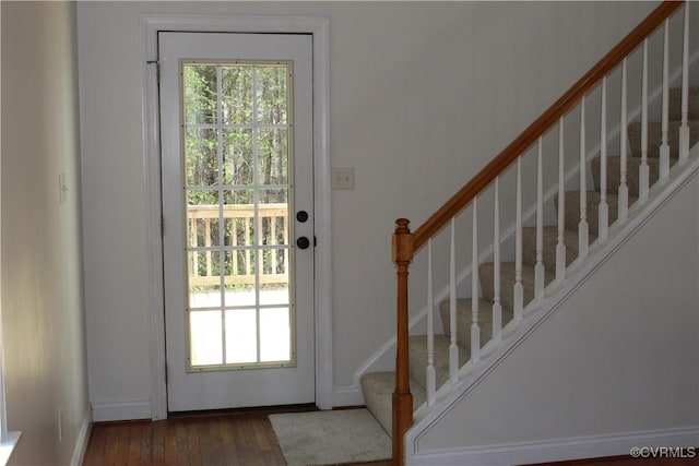 doorway featuring baseboards, stairway, plenty of natural light, and wood finished floors