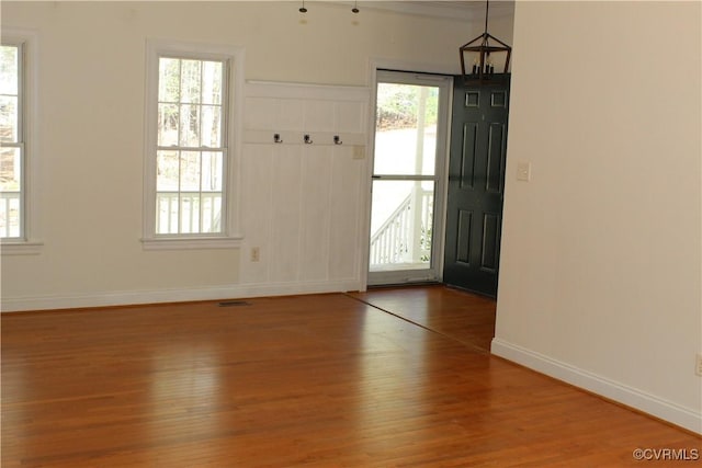 foyer entrance featuring baseboards, visible vents, and wood finished floors