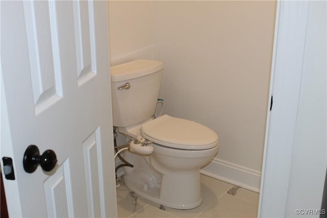 bathroom featuring toilet, marble finish floor, and baseboards