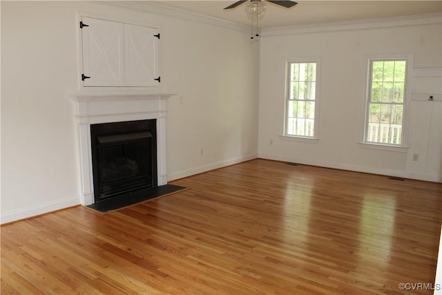 unfurnished living room featuring a ceiling fan, light wood-style flooring, baseboards, ornamental molding, and a fireplace with flush hearth