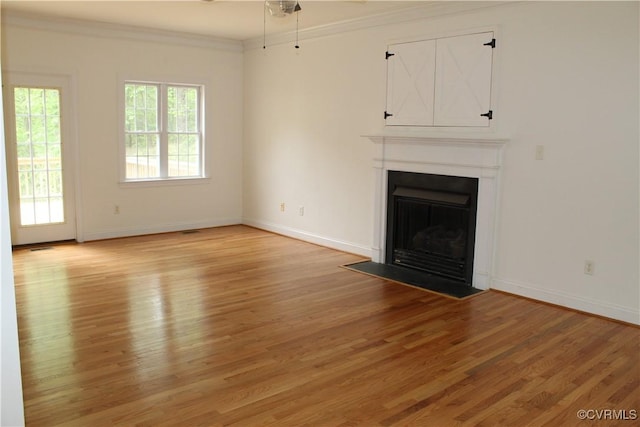 unfurnished living room with ceiling fan, ornamental molding, light wood-style flooring, and a fireplace with flush hearth