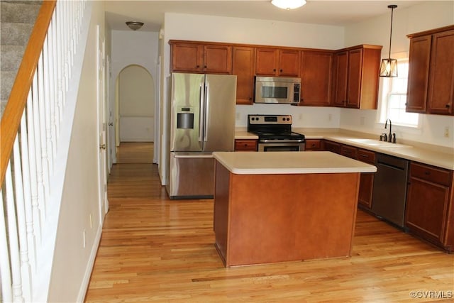 kitchen with a center island, a sink, appliances with stainless steel finishes, light countertops, and light wood-style floors
