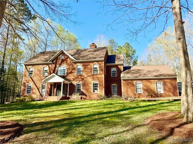 view of front of house with brick siding, a front lawn, and a chimney