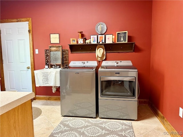 laundry area featuring independent washer and dryer, light tile patterned flooring, a sink, and baseboards