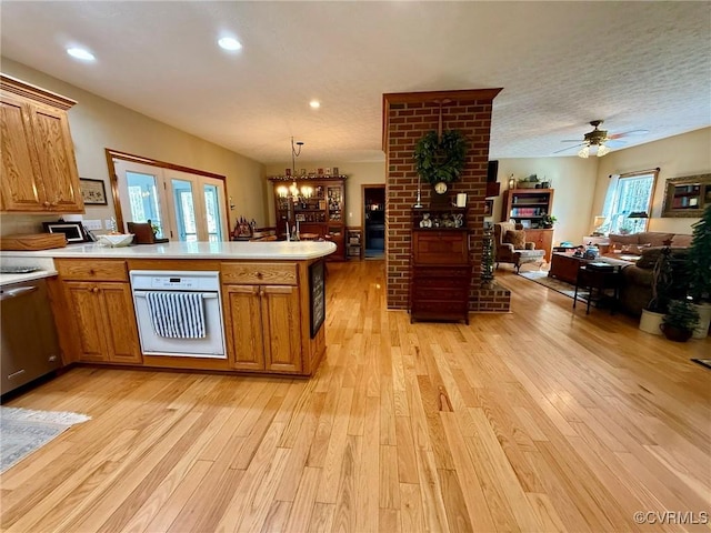 kitchen featuring light wood-type flooring, brown cabinets, oven, and a peninsula