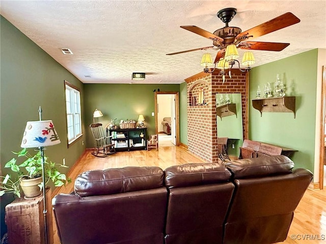 living room with ceiling fan, a textured ceiling, visible vents, and wood finished floors