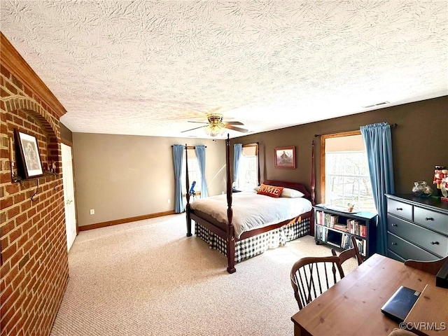 carpeted bedroom with ceiling fan, a textured ceiling, visible vents, brick wall, and baseboards