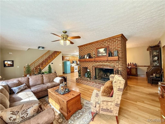 living area featuring ceiling fan, a textured ceiling, light wood-style floors, and stairs
