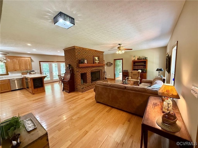 2222 Green Level Rd, King William, VA 23086 - living room featuring ceiling fan, a textured ceiling, light wood finished floors, a brick fireplace, and french doors