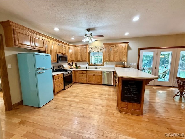 2222 Green Level Rd, King William, VA 23086 - kitchen featuring stainless steel appliances, a peninsula, brown cabinetry, light wood-style floors, and light countertops